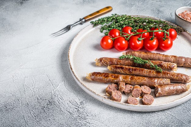 Salsicha de carne de cordeiro grelhada em um prato com ervas e tomate.