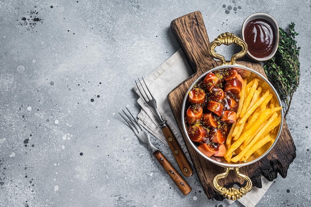 Salsicha de currywurst alemã tradicional servida com batatas fritas ou batatas fritas em uma panela Fundo cinza Vista superior Espaço para cópia