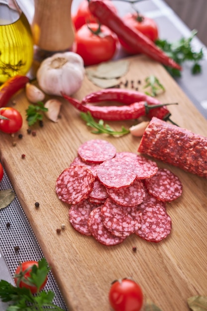 Salsicha de salame fatiada na tábua de madeira na cozinha doméstica