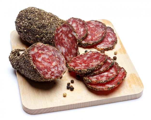 Salsicha de salame orgânico seco coberto com pimenta na tábua de madeira