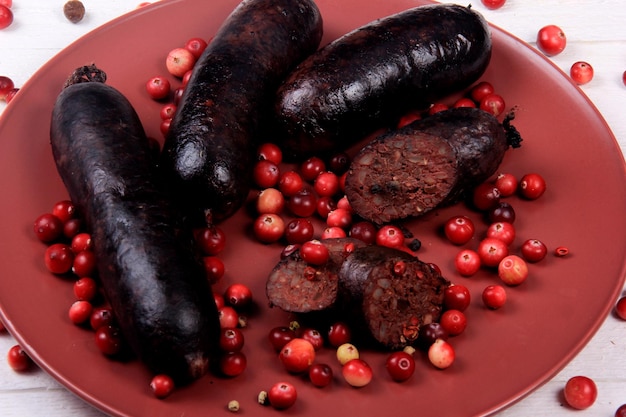 Salsicha de sangue assada em um prato vermelho decorado com cranberries vermelhos