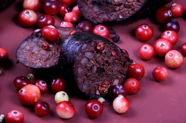 Salsicha de sangue assada em um prato vermelho decorado com cranberries vermelhos