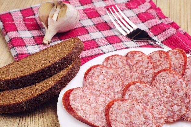 Salsicha defumada fatiada e pão na mesa de madeira