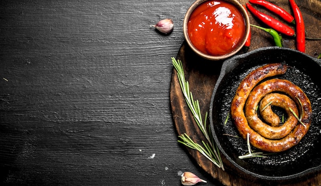 Salsicha em uma frigideira com molho de tomate quente no quadro negro