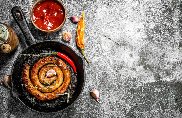 Salsicha em uma frigideira com pimenta, alho e molho na mesa rústica.