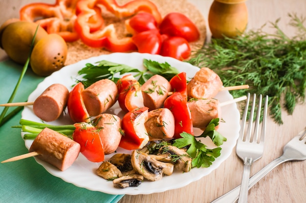 Salsicha frita com pimentos no espeto num prato