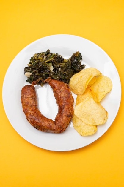 Foto salsicha fumada típica portuguesa frita com batatas fritas e espinafres