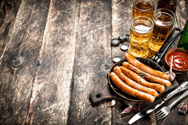 Foto salsichas com cerveja gelada e molho em fundo de madeira