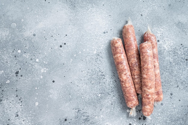 Salsichas cruas bratwurst em uma mesa de cozinha. fundo cinza. vista do topo. copie o espaço.