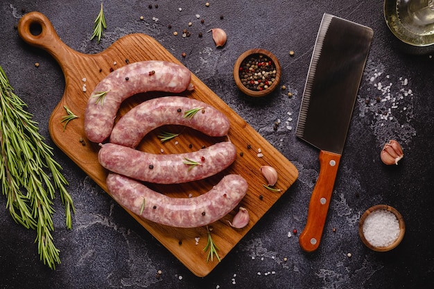 Salsichas cruas e ingredientes para cozinhar em uma mesa de pedra preta