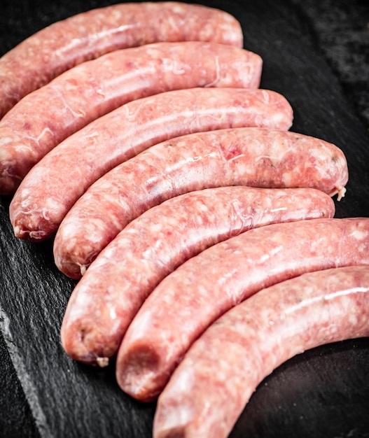 Salsichas cruas feitas de carne fresca em uma placa de pedra