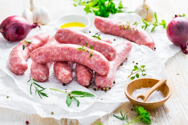 Salsichas cruas preparadas para churrasco e grelha com ervas e cebolas