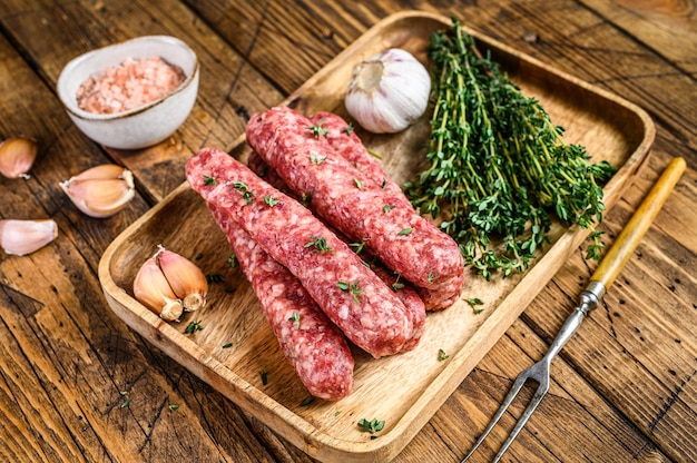 Salsichas de carne picada crua homamade em uma placa de corte.