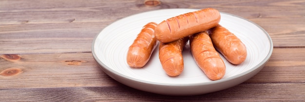 Salsichas de frango grelhado, prontas para comer em um prato sobre uma mesa de madeira