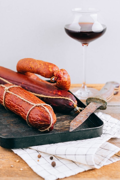 Foto salsichas defumadas sortidas, aperitivo de vinho tinto na madeira