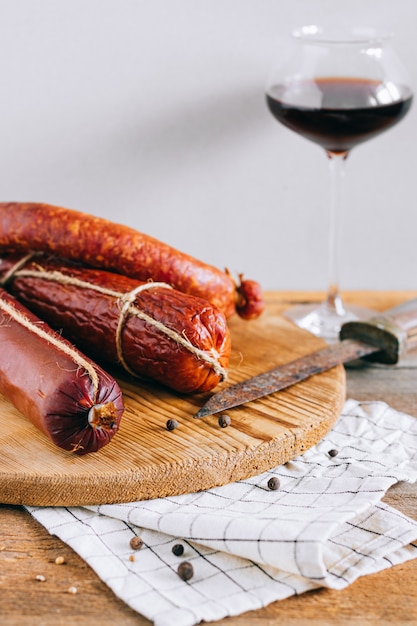 Foto salsichas defumadas sortidas, aperitivo de vinho tinto na madeira