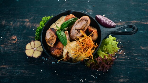 Salsichas em molho e legumes em uma frigideira Em uma mesa de madeira Vista superior Copiar espaço