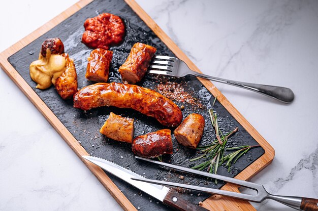 Salsichas fritas com molhos e especiarias num prato de pedra