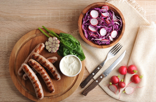 Salsichas fritas na grelha com molho de natas e uma salada de rabanete com repolho roxo