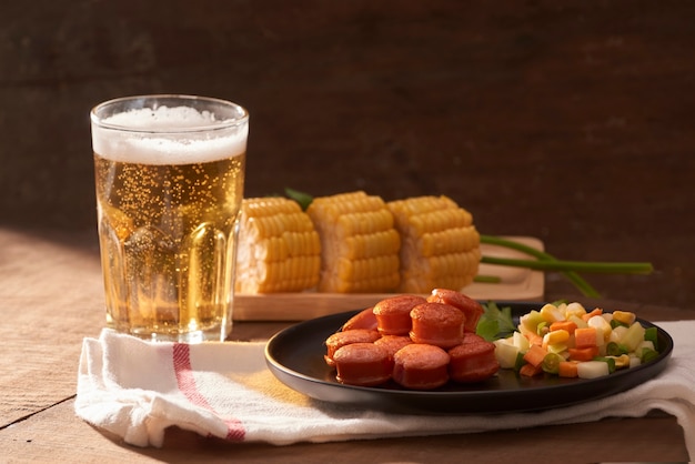 Salsichas grelhadas com copo de cerveja na mesa de madeira com espaço de cópia.