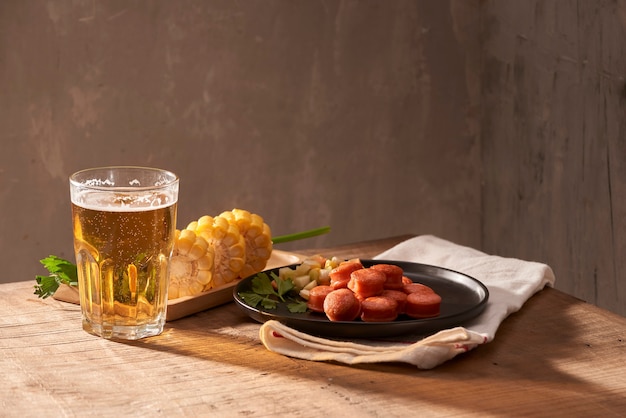 Salsichas grelhadas com copo de cerveja na mesa de madeira com espaço de cópia.