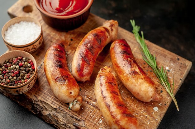 Salsichas grelhadas com especiarias, ketchup e alecrim em uma mesa de pedra, pronta para comer