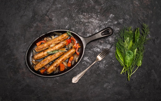 Salsichas na grelha pan no fundo de madeira Vista superior Frigideira com legumes de salsicha frita e garfo e faca em uma mesa de madeira rústica