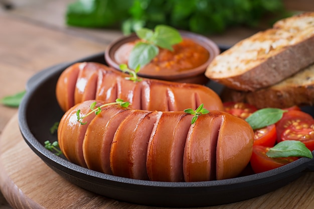 Salsichas na panela de grelhar na mesa de madeira