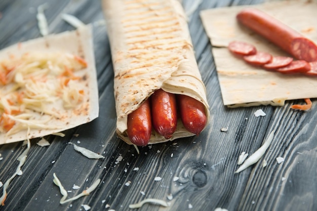 Salsichas picantes em pão pita em uma mesa de madeira