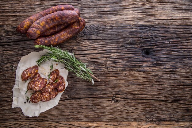 Salsichas. Salsicha defumada. Chouriço com especiarias de alecrim vegetal e utensílios de cozinha.