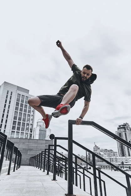 Foto saltando directamente sobre cualquier obstáculo. apuesto joven en ropa deportiva