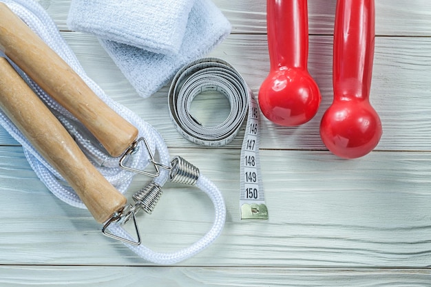 Saltar la cuerda bandas para el sudor mancuernas rojas cinta métrica en el concepto de fitness de tablero de madera.