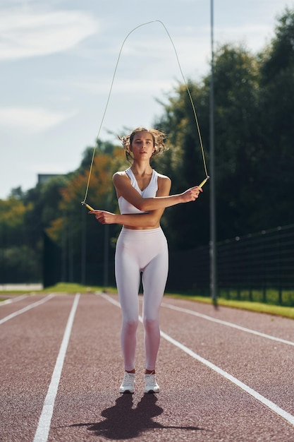 Saltar la cuerda Mujer joven en ropa deportiva está haciendo ejercicio al aire libre