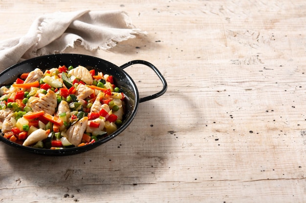 Salteado de pollo y verduras en mesa de madera