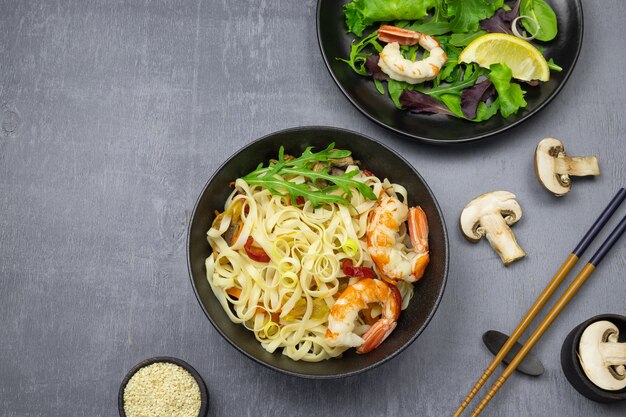 Saltear los fideos con verduras y camarones en tazones