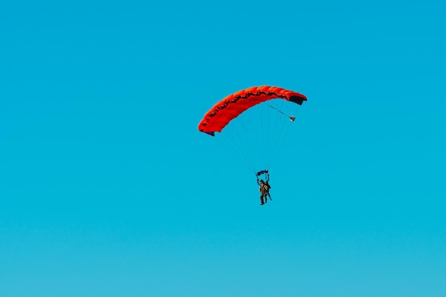 Salto de paraquedas em tandem Silhueta de paraquedista voando no céu azul claro