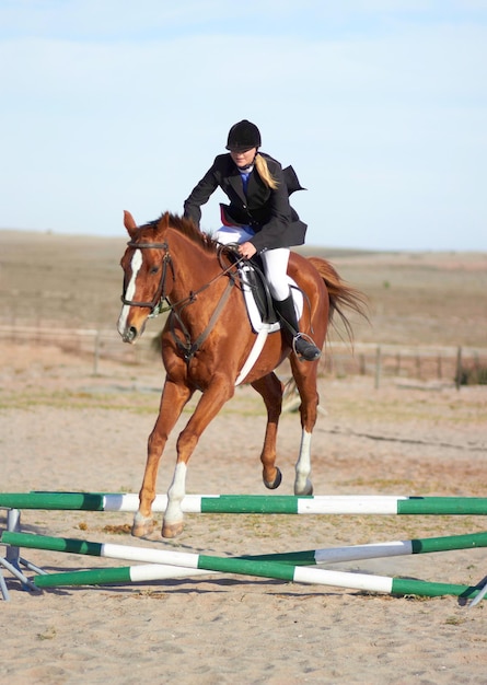 Salto deportivo y ecuestre con mujer a caballo para espectáculo de competencia y rendimiento Entrenamiento derby y salud con jockey femenina sobre animal en el campo para evento de obstáculos a caballo y jinete