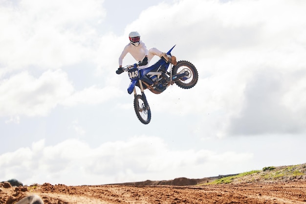 Salto esportivo e homem em motocicleta com energia de liberdade e acrobacias de poder no campo para desafio de treinamento Ar fora da estrada e salto masculino com motocicleta para desempenho de velocidade ou ação de Moto