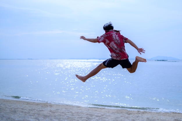 Salto joven en la arena cerca del mar