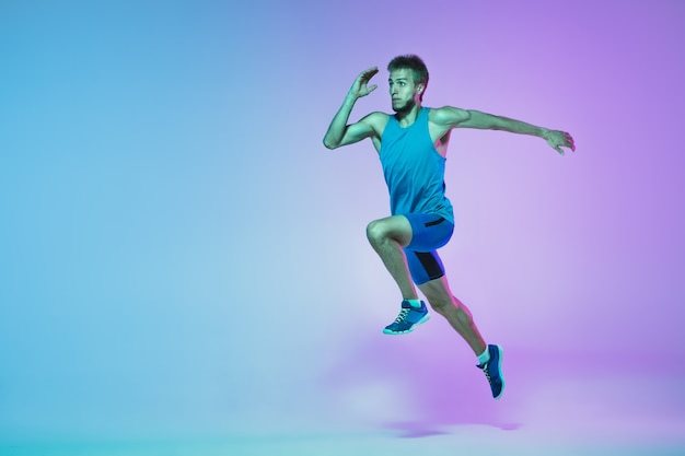 Foto en salto retrato de hombre caucásico joven corriendo trotar sobre fondo de estudio degradado