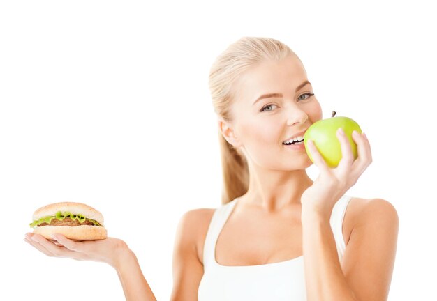 salud, belleza, pérdida de peso, comida, concepto de dieta - mujer deportiva con manzana y hamburguesa