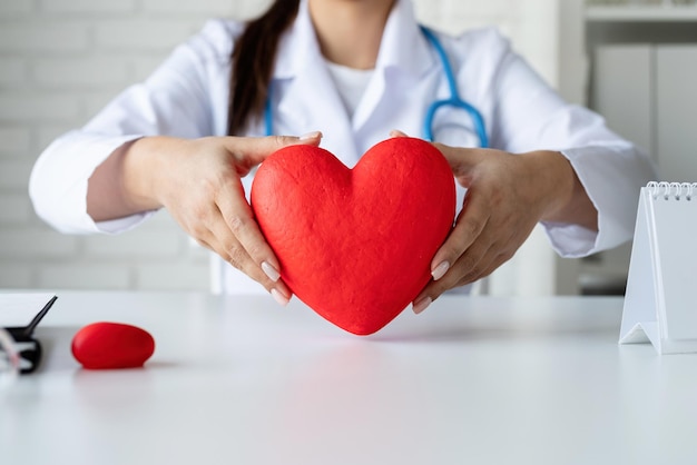 Salud, concepto de seguro. doctora o científica mujer sosteniendo un gran corazón rojo en las manos