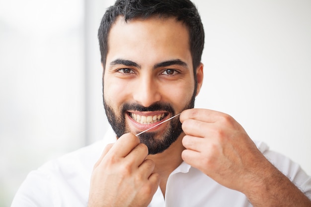 Salud dental. Hombre con hermosa sonrisa Flossing dientes sanos