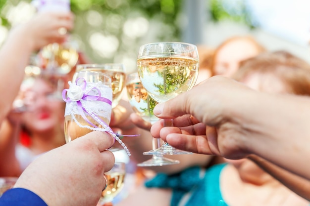 Salud. Grupo de personas bebiendo y brindando en el restaurante. Manos sosteniendo copas de champán y brindis de elaboración de vino.