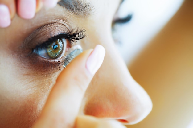 Salud Joven sostiene un dedo Lente de contacto Retrato de una mujer hermosa con ojos verdes