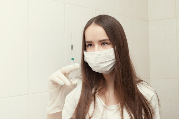 Salud y medicina La doctora con mascarilla y guantes sostiene una jeringa con una vacuna