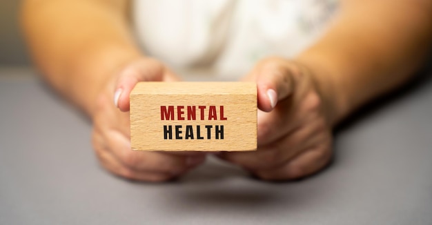 Foto salud mental en bloques de madera en manos femeninas bienestar psicológico y social emocional que influye en la cognición, la percepción y el comportamiento trastorno de depresión y ansiedad
