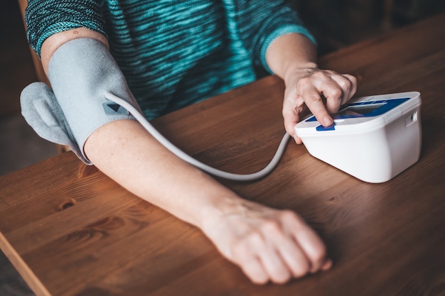 La salud de la mujer controla la presión arterial y la frecuencia cardíaca en casa con presión digital, concepto médico y de salud