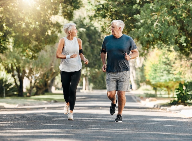 Salud pareja senior y correr mientras hablan y hacen ejercicio para el bienestar físico y saludable juntos en la naturaleza El hombre y la mujer jubilados disfrutan de hacer ejercicio charlando y trotando afuera en el parque en un día soleado