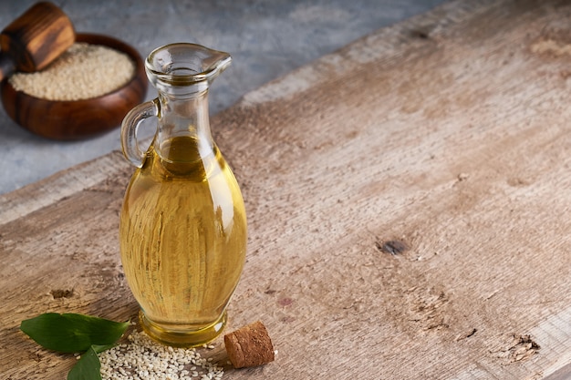 Saludable aceite de sésamo en botella de vidrio y semillas de sésamo en mesa de madera Copia espacio Rústico